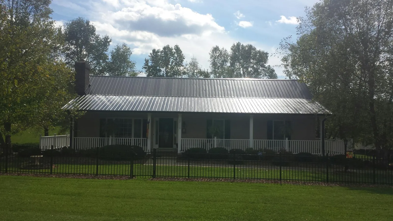 Gray metal roof on a brick ranch with a full width front porch — Gutter Guard Installation work by our crew in Seminole